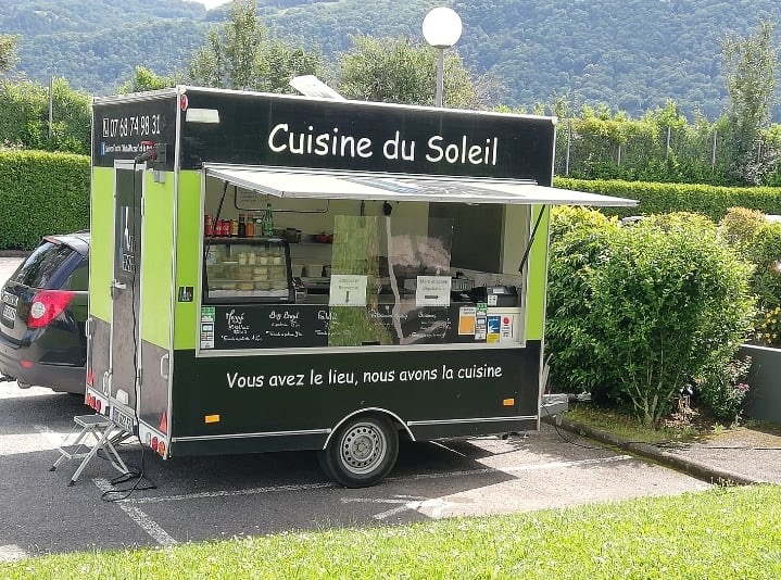 Un camion aux couleurs vertes et noires sur un parking. Ce camion vend des mezze, des falafels et des bagels.